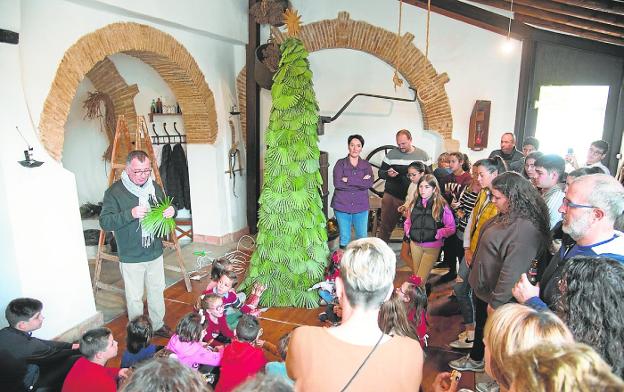 Los asistentes al encuentro en la Casa del Folclore visten el árbol navideño. / A. GIL / AGM