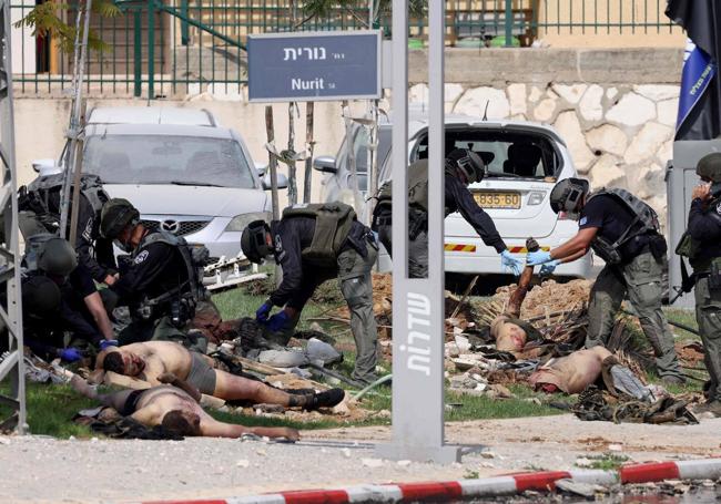 Un grupo de policías examina los cadáveres de varios combatientes palestinos frente a una comisaría en la ciudad israelí de Sderot.