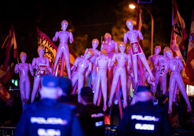 Varios manifestantes con muñecas hinchables y banderas frente a los policías que vigilaban Ferraz este lunes.