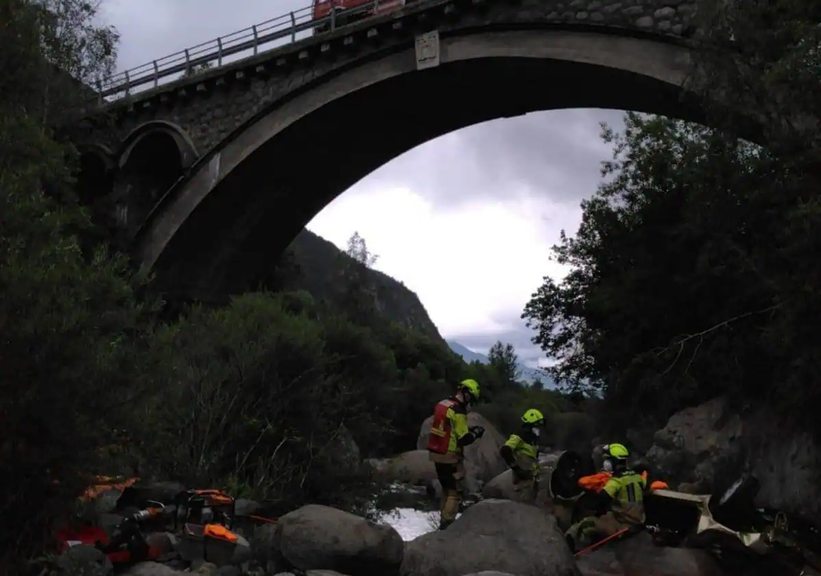 Imagen principal - Vista de la zona del accidente desde el río Ésera y trabajos de los bomberos para tratar de rescatar del coche siniestrado los cuerpos de las tres víctimas mortales.