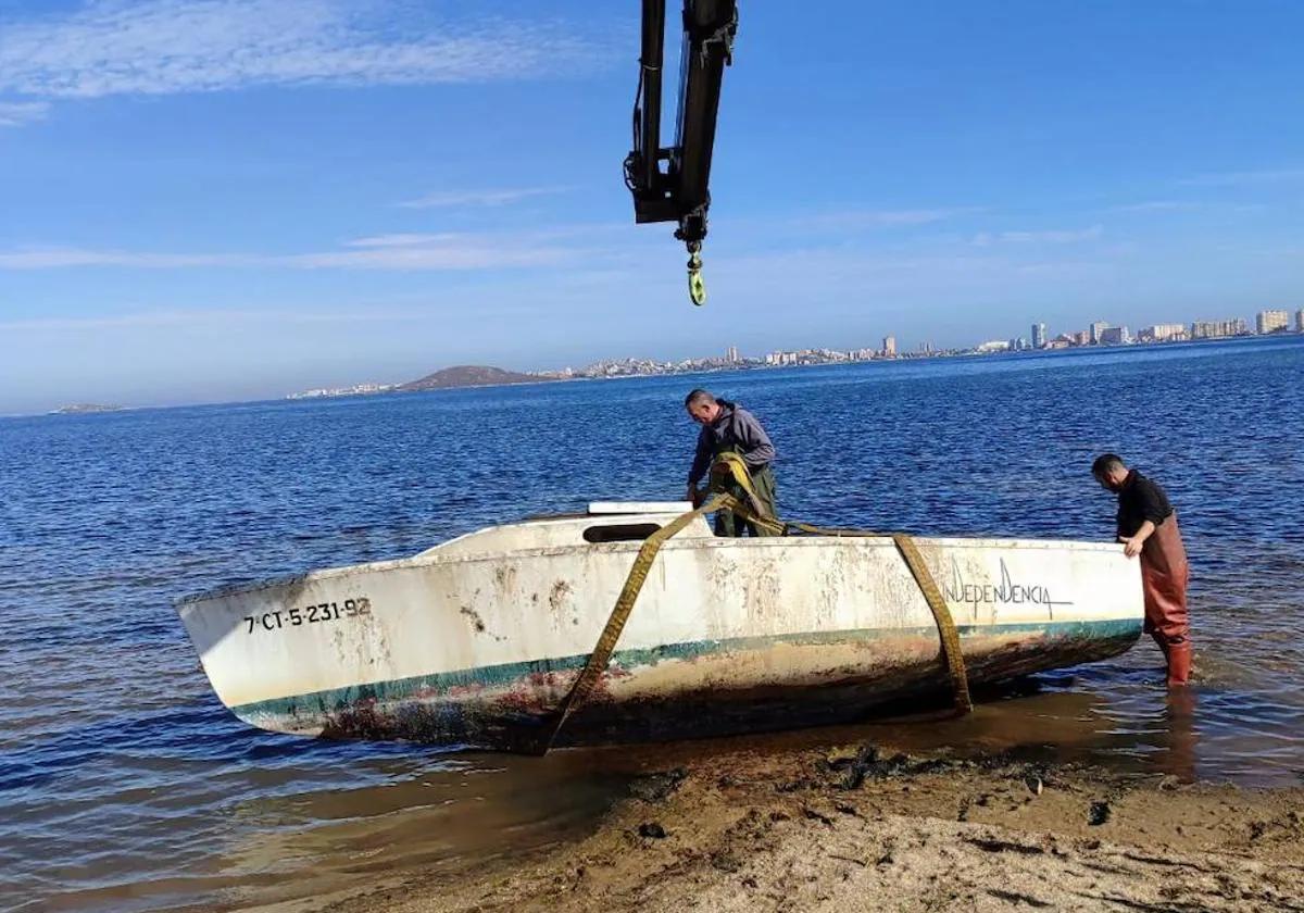 Dos pescadores preparan un barco para su retirada con una grúa, entre Punta de Lomas y Mar de Cristal.