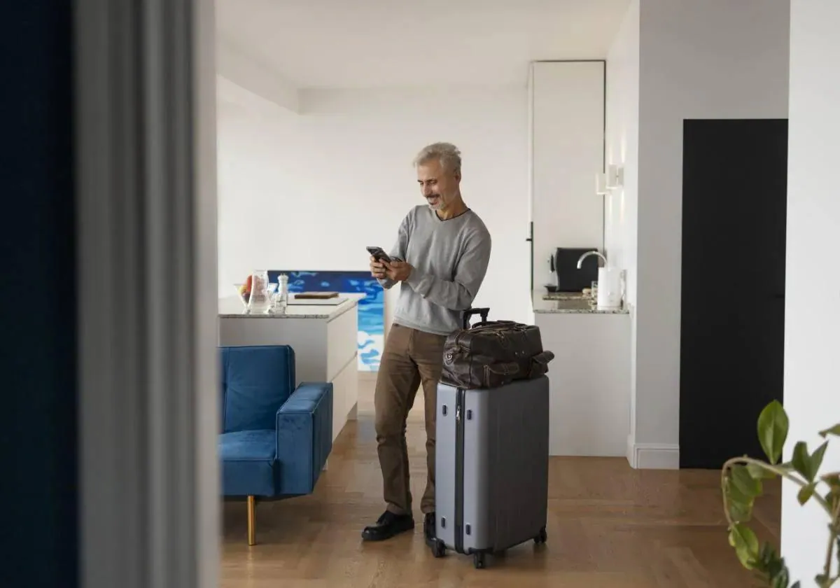 Un viajero consulta su teléfono móvil en un apartamento turístico.