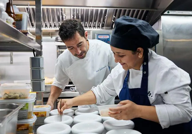 El chef del restaurante Almo, Juan Guillamón, junto a Karla, auxiliar de cocina formada en la escuela de hostelería de Cáritas. Abogada de 33 años, tuvo que salir de Honduras a causa de la violencia.