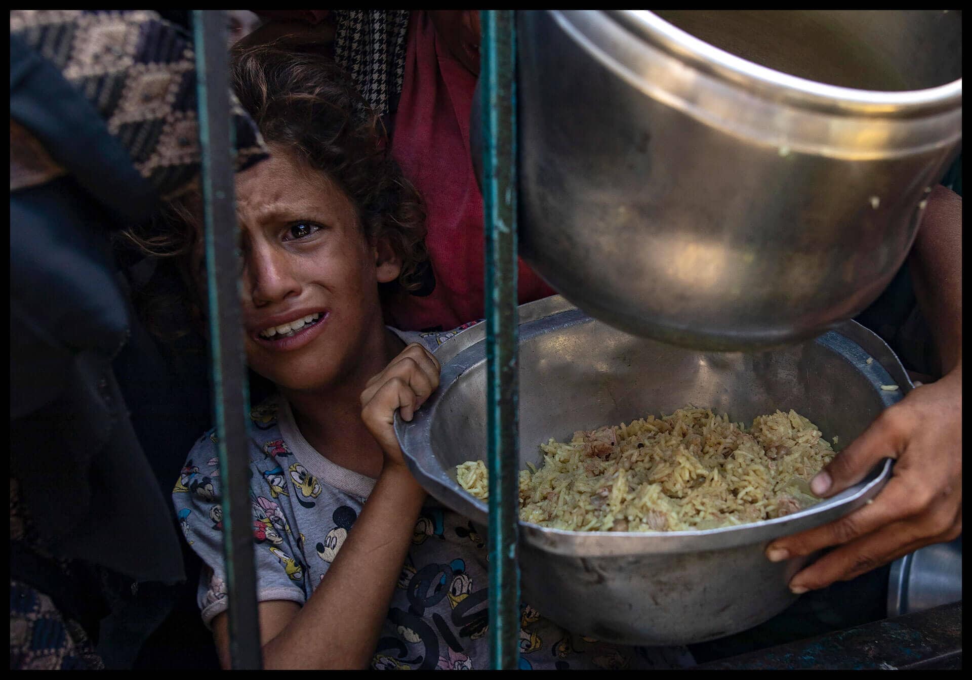 Una niña recioge alimento donado por una organización benéfica en el campamento de Khan Yuni.