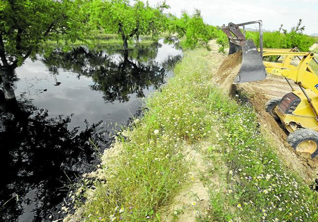 Una pala arroja tierra sobre uno de los charcos de petróleo formados entre los almendros, en los Llanos del Cagitán.