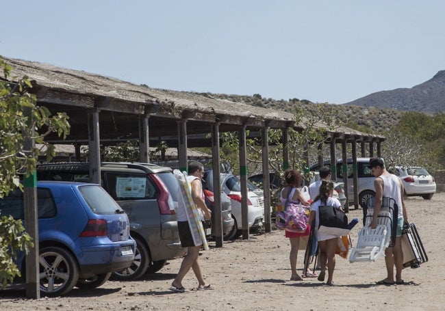 Unos bañistas salen del parking de El Atochar, tras dejar el coche, en dirección a la playa.