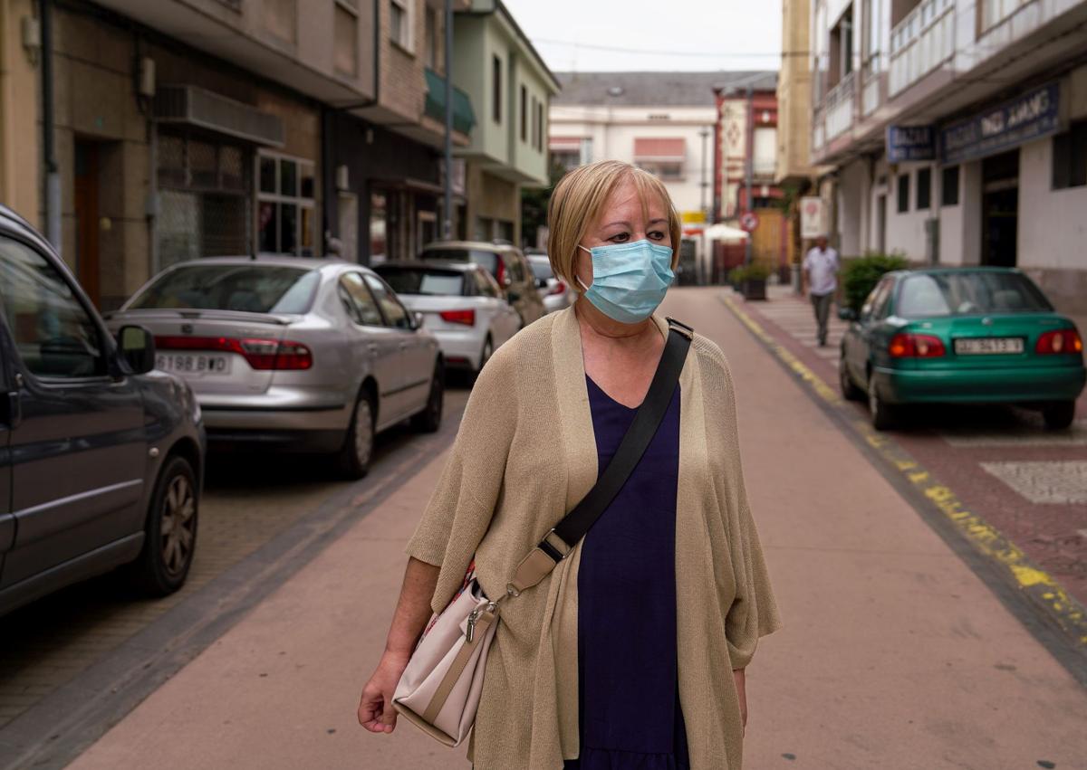 Imagen secundaria 1 - Arriba, el cartel que indica la entrada al vertedero. Abajo, una mujer caminando con la mascarilla por el humo y una farmacia de A Rúa.