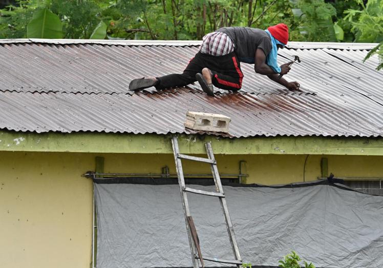 Un joven se apresura a apuntalar el tejado de su casa.