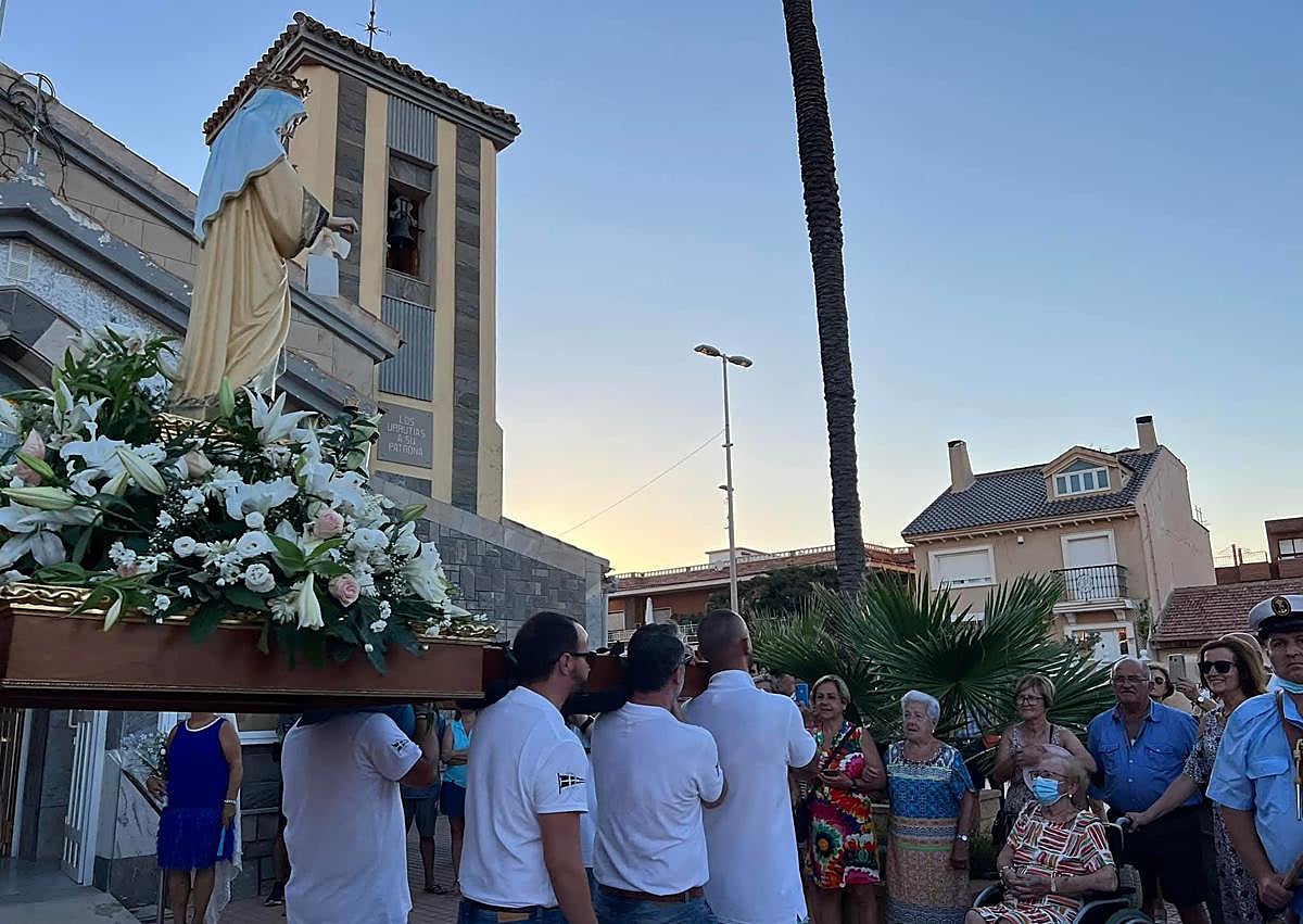 Imagen secundaria 1 - La imagen de la patrona de Los Urrutias, frente a la iglesia y montada en un barco durante el día de su romería.
