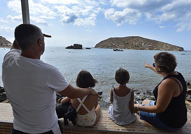 Una familia contempla la playa, con la isla de Adentro al fondo.