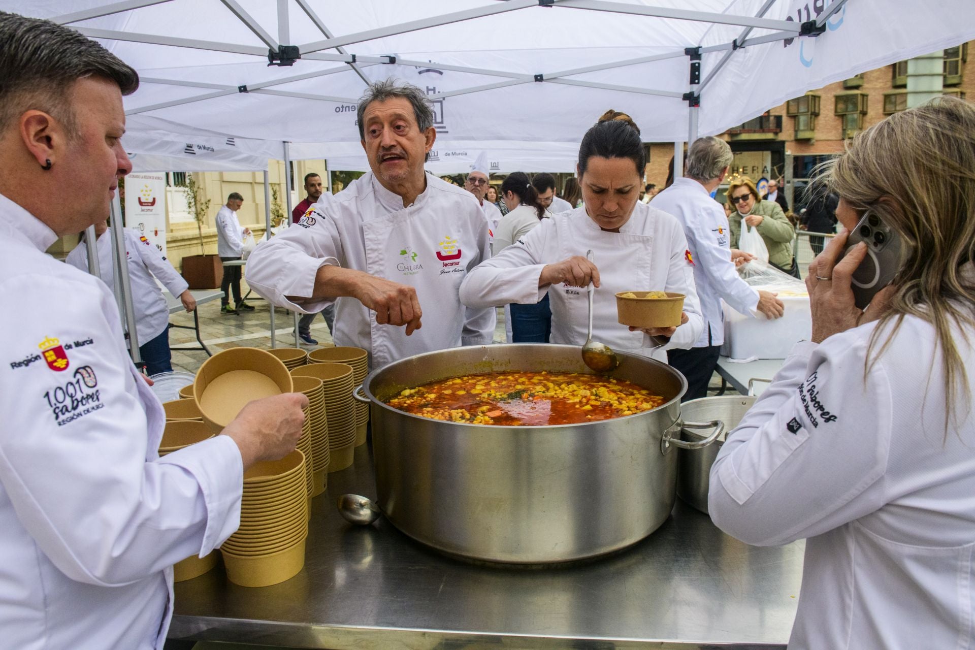 Los cocineros preparan las raciones de cocido, este domingo, en la Plaza Julián Romea de Murcia.