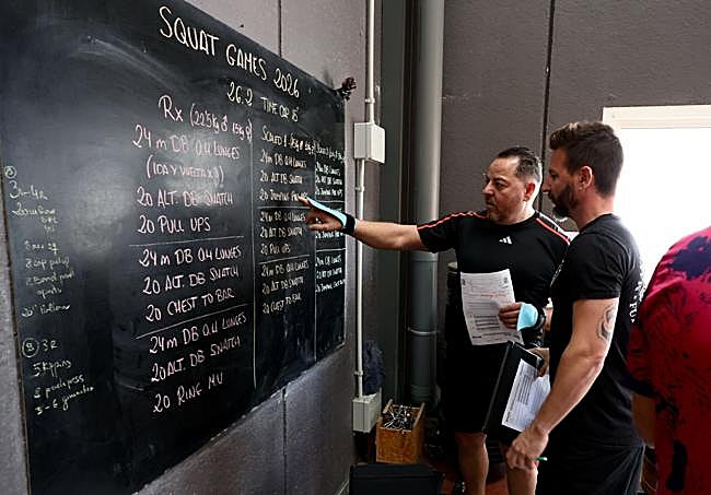 Mirar la pizarra y no abandonar. Dos usuarios de SquatMaster Box conocen el reto del día.