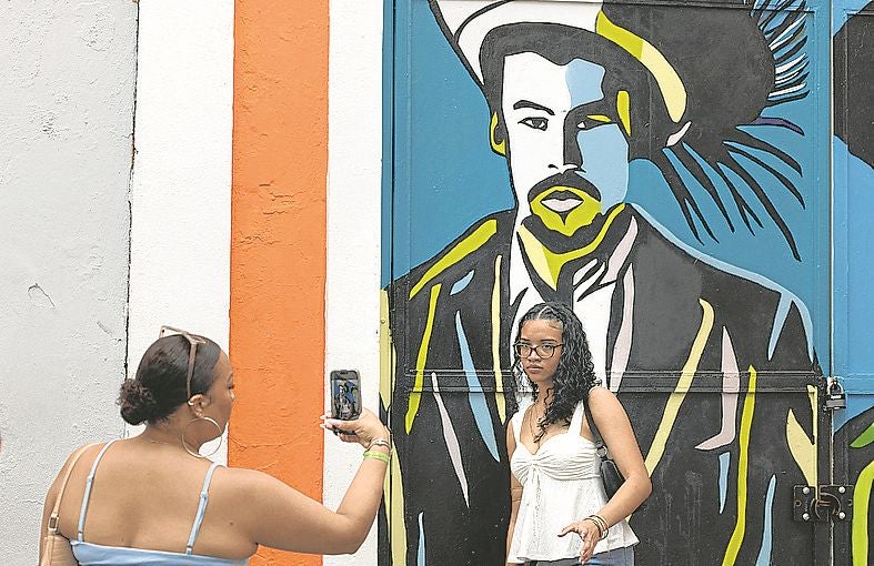 Una mujer posa frente a un mural del artista en el Viejo San Juan.
